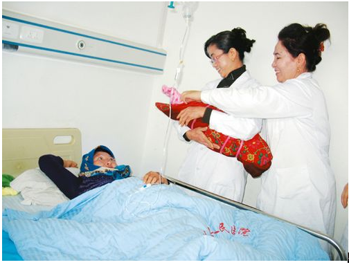 图为余文丽(右二)和医生来到病房看望难产产妇和新生儿。(记者 马燕 摄)